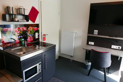 a small kitchen with a sink and a desk at Hotel Gasthof Handewitt in Handewitt