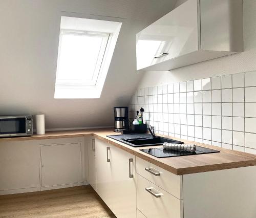 a kitchen with white cabinets and a window above a stove at CITYNA Apartment Bielefeld in Bielefeld