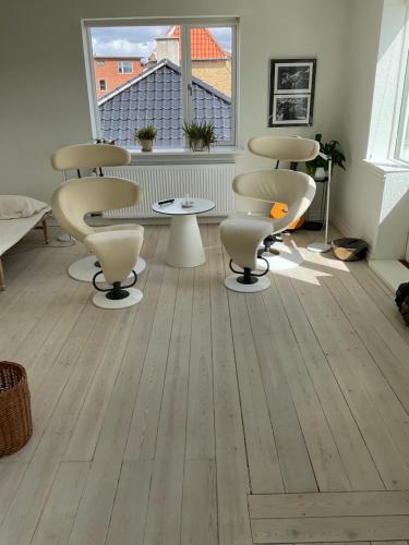 um salão com cadeiras e uma mesa num quarto em Stor lys lejlighed med terrasse og altan em Helsingør
