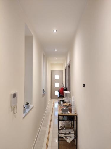 um corredor com paredes brancas e uma fileira de mesas em Room Sixty One em Palermo