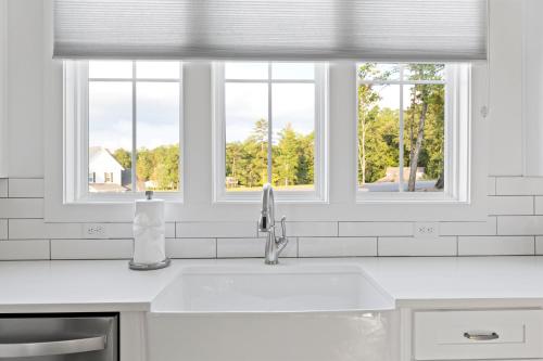 cocina blanca con fregadero y 3 ventanas en High Cotton on Lake Martin, en Dadeville