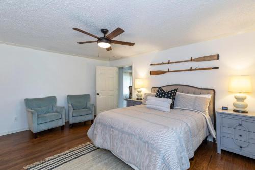 a bedroom with a bed with a ceiling fan and two chairs at Abigail's Lake Haven in Jacksons Gap