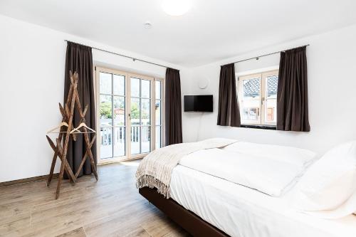 a white bedroom with a large bed and windows at Ferienwohnung Höfle in Garmisch-Partenkirchen