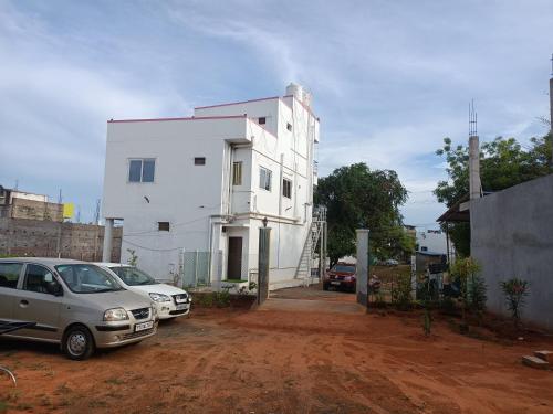 a white house with two cars parked in front of it at Guru Residency Pondicherry in Puducherry