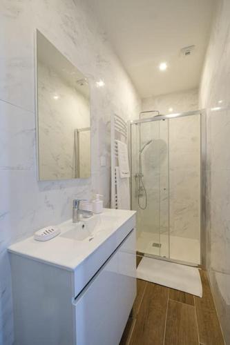 une salle de bain blanche avec un lavabo et une douche dans l'établissement Villa Forestière Appart. Le Paulownia, à Quincy-Voisins