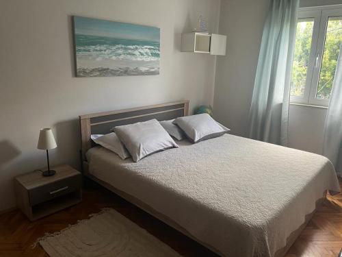 a bedroom with a bed with white sheets and a window at Apartment Frane in Kaštela