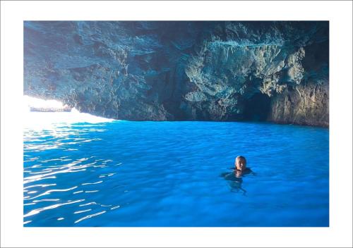 a person in the water in front of a blue cave at VatiKurca in San Nicola Arcella