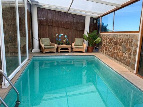 a swimming pool in a house with a patio with chairs at Villa Cantos del Grillo in Ingenio
