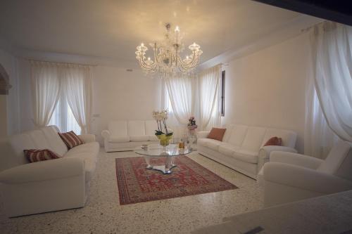 a living room with white furniture and a chandelier at Country House Giusti Abazia in Nervesa della Battaglia