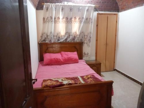 een slaapkamer met een houten bed met roze lakens bij Merit Roof Apartment in Hurghada