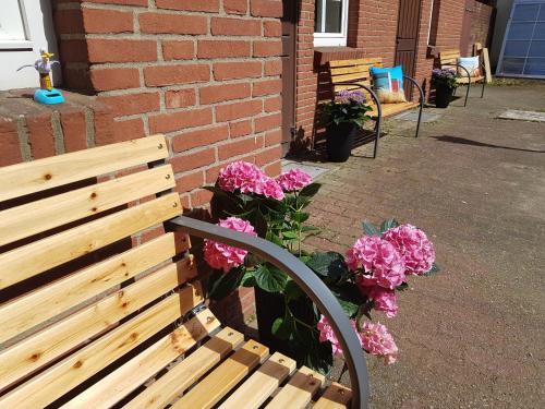 a wooden bench with pink flowers next to a brick building at Sleeptide in Husum