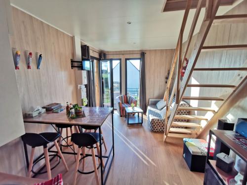 uma sala de estar com uma mesa e cadeiras e uma escadaria em Agréable Tiny house à la campagne 