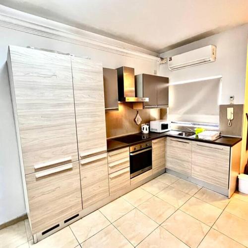 a large kitchen with wooden cabinets and appliances at Gzira Smart 1 Bedroom Apartment in Il-Gżira