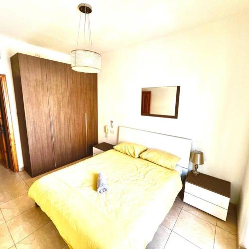 a bedroom with a large bed with a yellow blanket at Gzira Smart 1 Bedroom Apartment in Il-Gżira