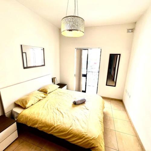 a bedroom with a large bed with a yellow blanket at Gzira Smart 1 Bedroom Apartment in Il-Gżira