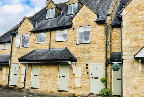 a brick house with white doors and a black roof at Stunning Apartment In The Heart of Broadway in Broadway