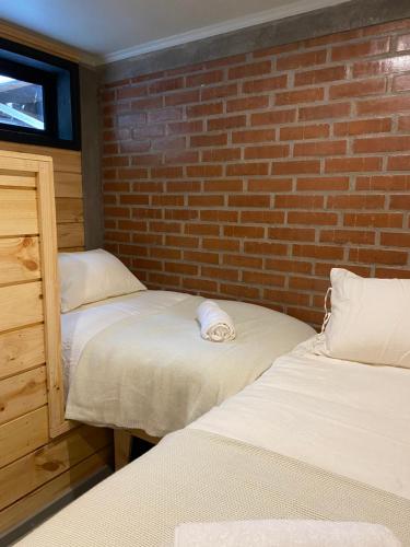 two beds in a room with a brick wall at Cabañas La Matanza in Matanzas
