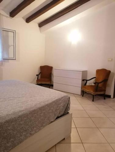 1 Schlafzimmer mit einem Bett und 2 Stühlen in der Unterkunft Bilocale a 15 min da Alassio e Albenga in Ranzo-Borgo