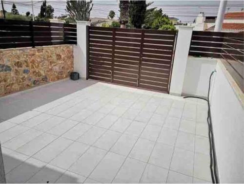 a patio with a wooden fence and a white tile floor at Bahia Homes Torrevieja in Torrevieja