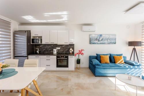 ein Wohnzimmer mit einem blauen Sofa und einer Küche in der Unterkunft Villa Carpe diem in Vodice
