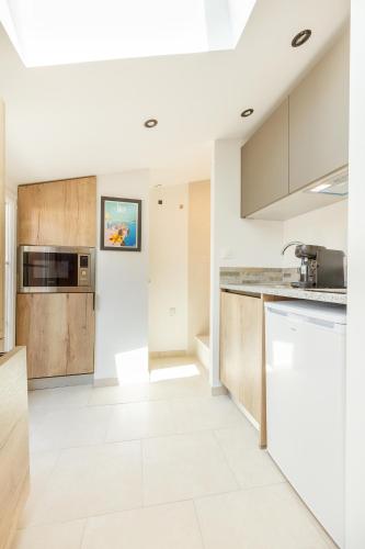 - une cuisine avec des murs blancs et des placards en bois dans l'établissement Roche 5, à Toulon