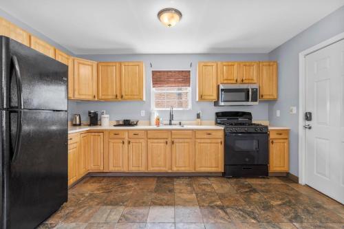 a kitchen with wooden cabinets and a black refrigerator at Gorgeous Waterfront 3 Bedroom, 1.5 Bathroom Unit. in New Haven