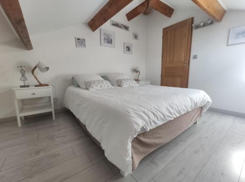 a white bedroom with a large bed and a wooden floor at L'Ansolane in Fuveau