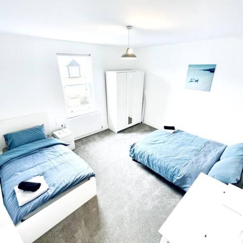 um quarto com 2 camas e lençóis azuis em 2 Bedroom Modern House in Cambridge city centre em Chesterton