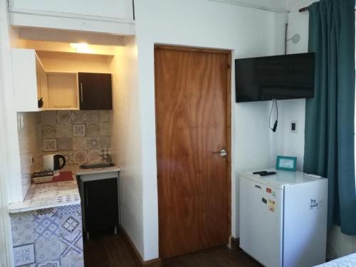 a small kitchen with a refrigerator and a wooden door at HOTEL Boutique Casablanca Adrogué in Adrogué