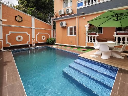 a swimming pool with a table and an umbrella at Agbata Guest House 