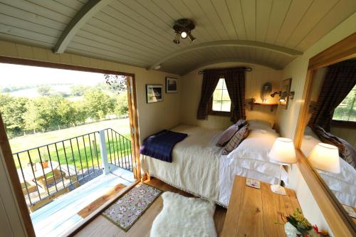 a bedroom with a bed and a balcony at Upper Gelli Luxury Holiday Lodge, Converted Dairy & Cosy Shepherds Huts in Welshpool