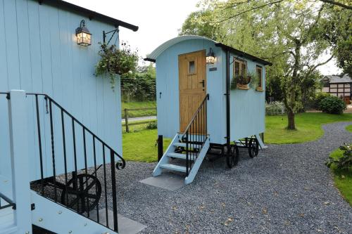 a tiny house with a staircase leading to a door at Upper Gelli Luxury Holiday Lodge, Converted Dairy & Cosy Shepherds Huts in Welshpool
