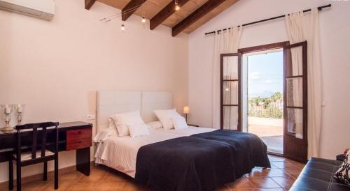 a bedroom with a bed and a desk and a window at Finca Cari in Can Picafort