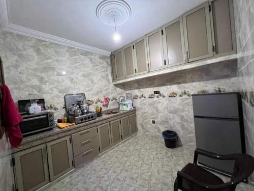 a kitchen with white cabinets and a black refrigerator at Appartement Sable D'or in Tan-Tan