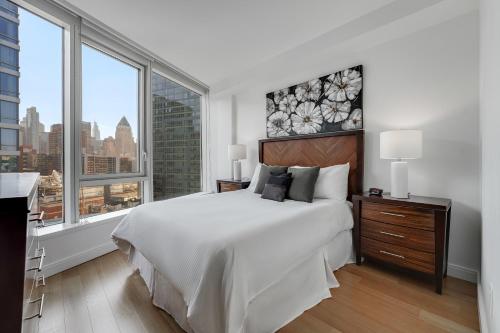 biała sypialnia z dużym łóżkiem i dużymi oknami w obiekcie Global Luxury Suites at Via 57 w Nowym Jorku