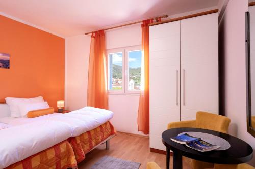 a bedroom with a bed and a table and a window at Apartments Bodlović in Hvar