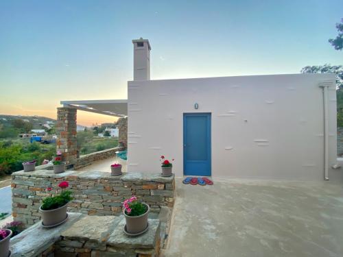 Charming Vourkari Stone Home 3 - Minutes from Port في Vourkari: مبنى ابيض بباب ازرق وبعض النباتات