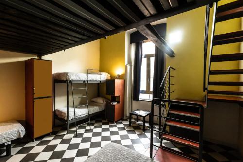 a room with bunk beds and a checkered floor at Fabric Hostel in Portici