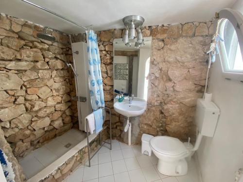 bagno in pietra con servizi igienici e lavandino di Casa Tortuca a Lampedusa