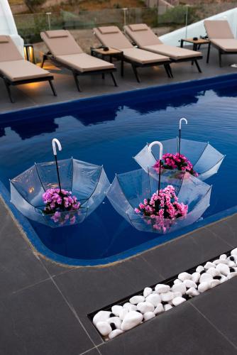 two umbrellas in a pool of water with flowers at Villa Concha Con Perla in Monolithos