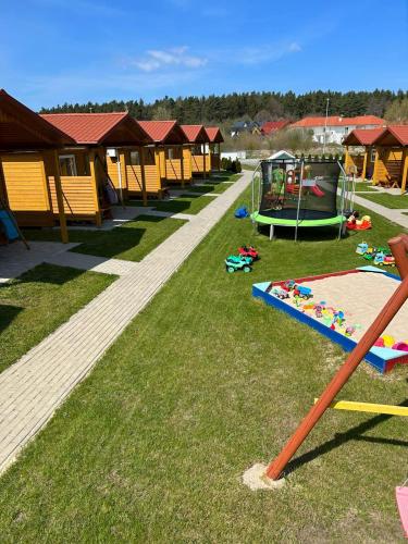 een speeltuin met een stel speeltoestellen in het gras bij Domki Milka in Ustka