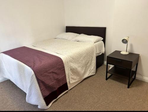 a bedroom with a bed and a table with a lamp at Gracelink in Erith