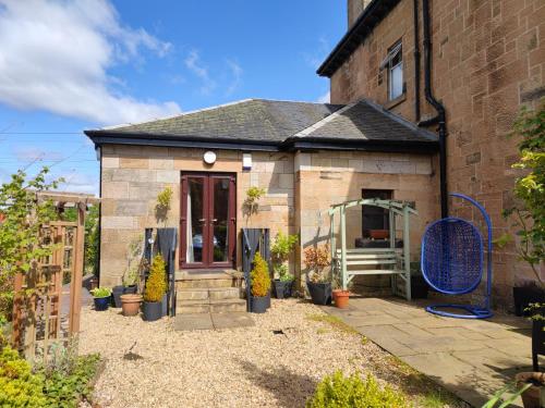 a small brick building with a patio with potted plants at Beautiful self contained apartment with garden in Glasgow