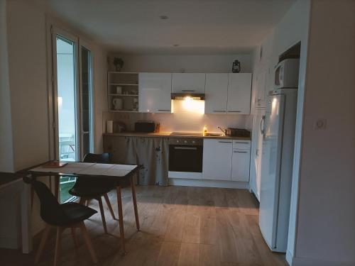 a kitchen with white cabinets and a table with chairs at LE LAVARIN Balcon et Parking privé WIFI in Avignon