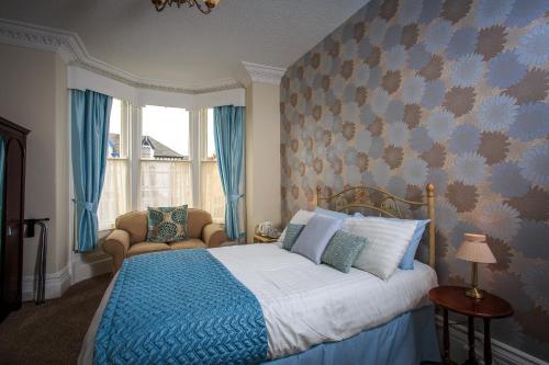 a bedroom with a blue bed and a window at Arvon House in Llandudno