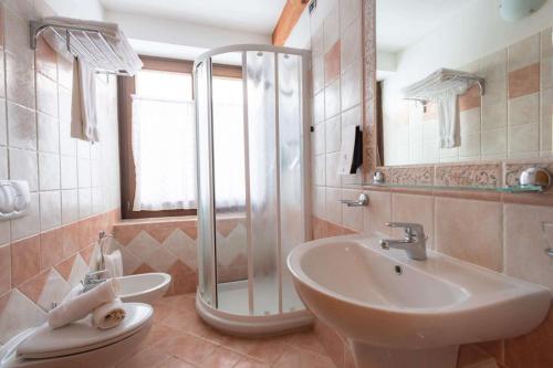 uma casa de banho com um chuveiro, um lavatório e um WC. em Hotel Angelo em Passo del Tonale