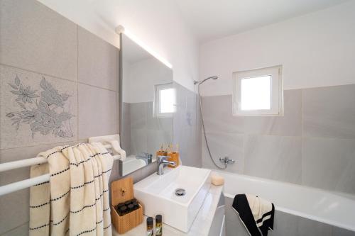 a white bathroom with a sink and a bath tub at Emelia Cozy Apartment in Rhodes Town