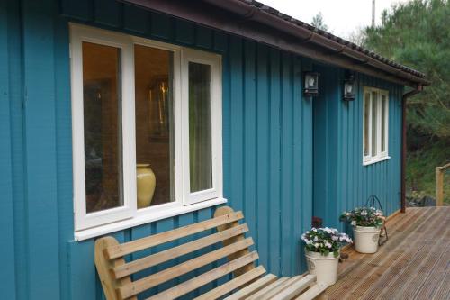 a blue house with a bench on a deck at Upper Gelli Luxury Holiday Lodge, Converted Dairy & Cosy Shepherds Huts in Welshpool
