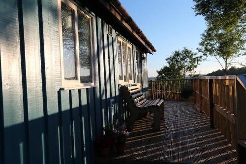 a bench sitting on the porch of a house at Upper Gelli Luxury Holiday Lodge, Converted Dairy & Cosy Shepherds Huts in Welshpool