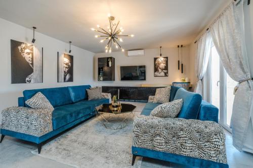a living room with a blue couch and two chairs at Holiday House Paula in Privlaka